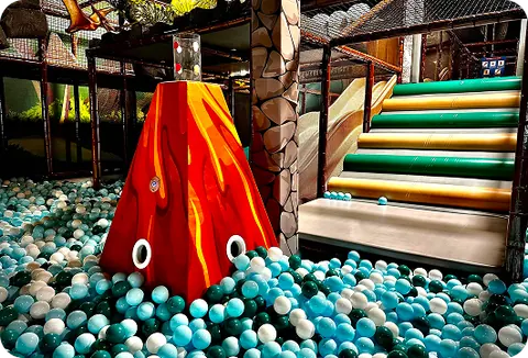 The walled toddler area at Dinotopia, with soft play shapes and low climbing steps on padded flooring