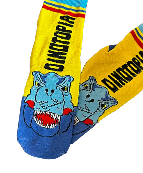 Bright yellow Dinotopia grip socks with a blue T-rex face and the Dinotopia wordmark